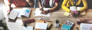 image of lots of students arms sitting around a table with books in front of them