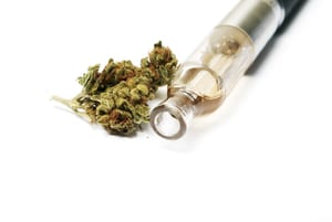 image of the cartridge end of a vaporizer next to a small bud of marijuana