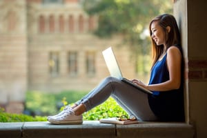 image of a student on a college campus sitting with her computer in her lap