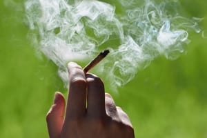 image of a hand holding a joint with smoke around their hand, demonstrating religious use of cannabis