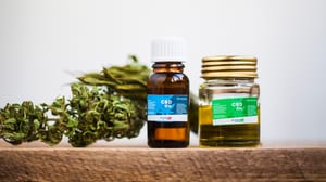 image of cbd oil and some flower sitting on a wood table to show that smoking weed low in THC, or with no THC at all, can help you avoid red eyes from weed