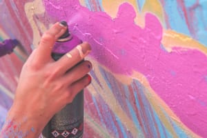 image close-up on a graffiti artist's hand as they paint a mural