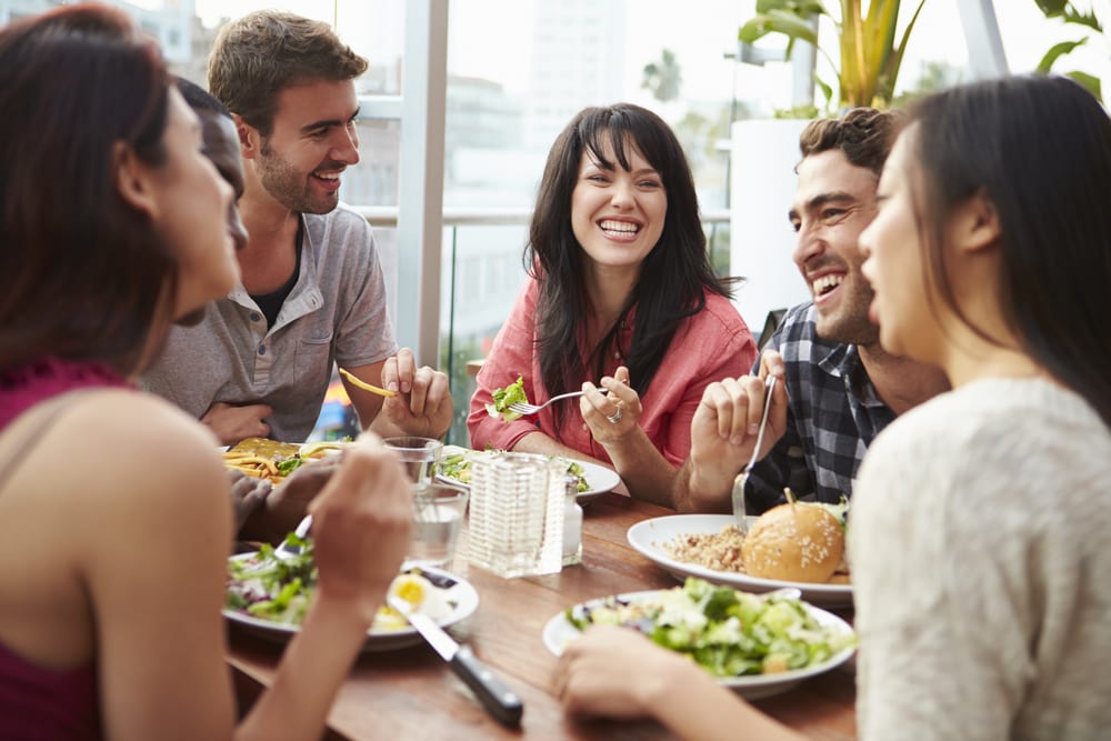 photo of friends sitting down having a meal together and smiling
