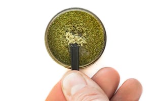 photo of a grinder that has a kief collector, with someone lifting kief out to show what it looks like