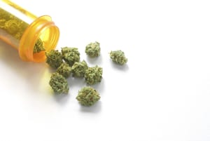 image of marijuana buds falling out of a pill bottle onto a table
