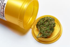 photo of a marijuana bud coming out a gold prescription bottle labeled "medical cannabis"