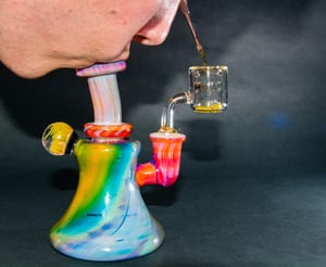 image of a man taking a marijuana dab out of a rainbow-colored rig