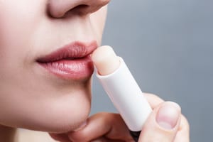 photo of a woman putting on unmarked lip balm