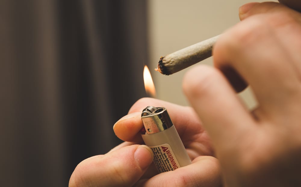 person lighting a marijuana joint