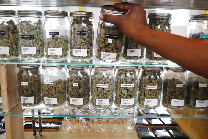 Election 2018 Marijuana In this Tuesday, Oct. 2, 2018, photo, a clerk reaches for a container of marijuana buds for a customer at Utopia Gardens, a medical marijuana dispensary, in Detroit. Michigan and North Dakota, where voters previously authorized medical marijuana, will decide now if the drug should be legal for any adult 21 and older. They would become the 10th and 11th states to legalize so-called recreational marijuana since 2012. (AP Photo/Carlos Osorio)