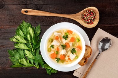 image of chicken noodle soup with a piece of bread and a spoon next to the bowl to show how delicious soup with cannabis can be